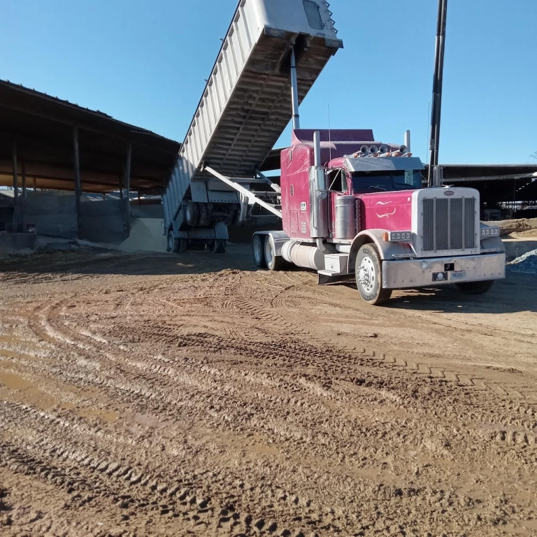 Red truck unloading cargo in construction site.