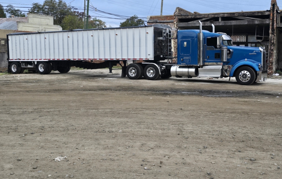 Blue semi-truck parked near brick building.
